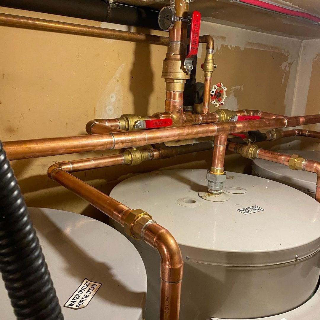 A close up of a water heater with copper pipes coming out of it.