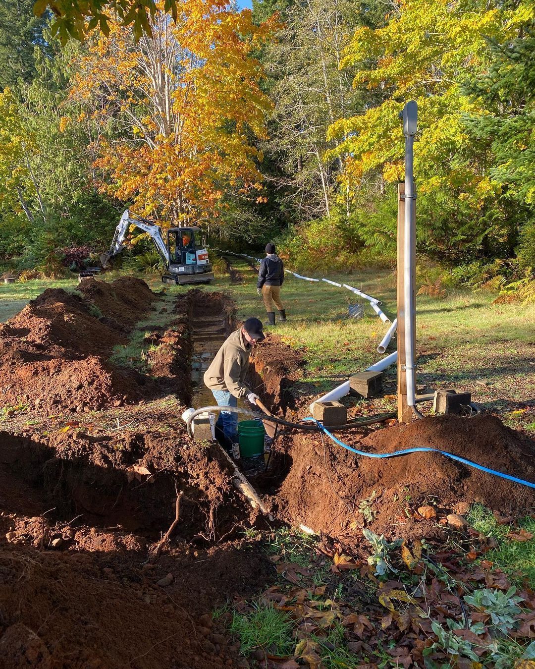 A man is digging a hole in the ground in a field.