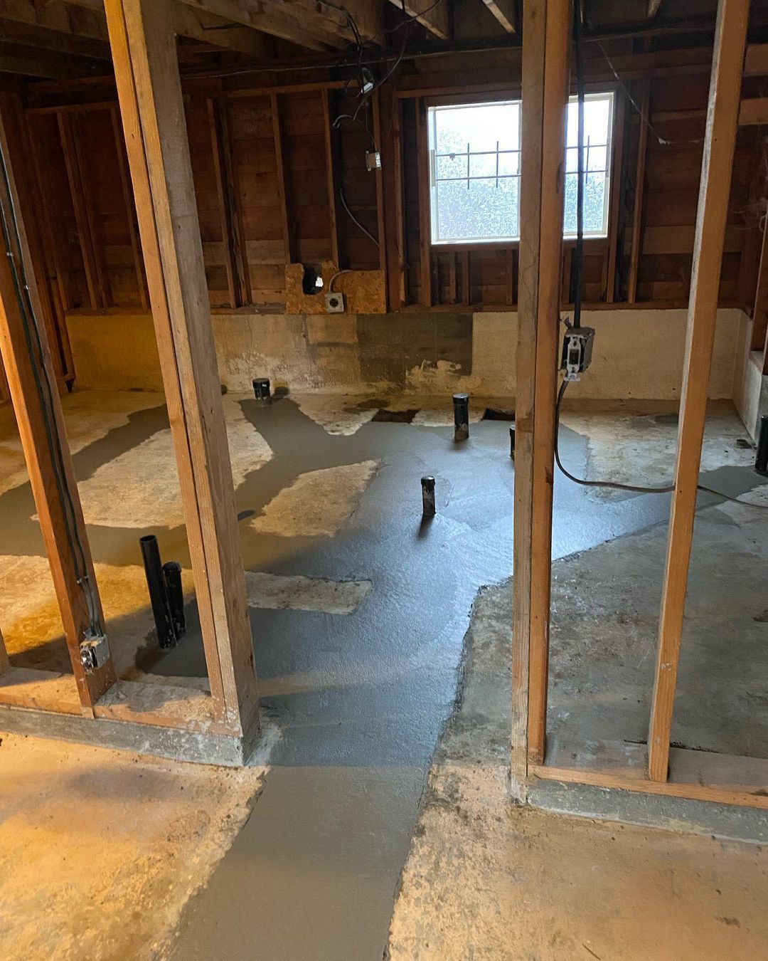 A room with a lot of wooden beams and a concrete floor.