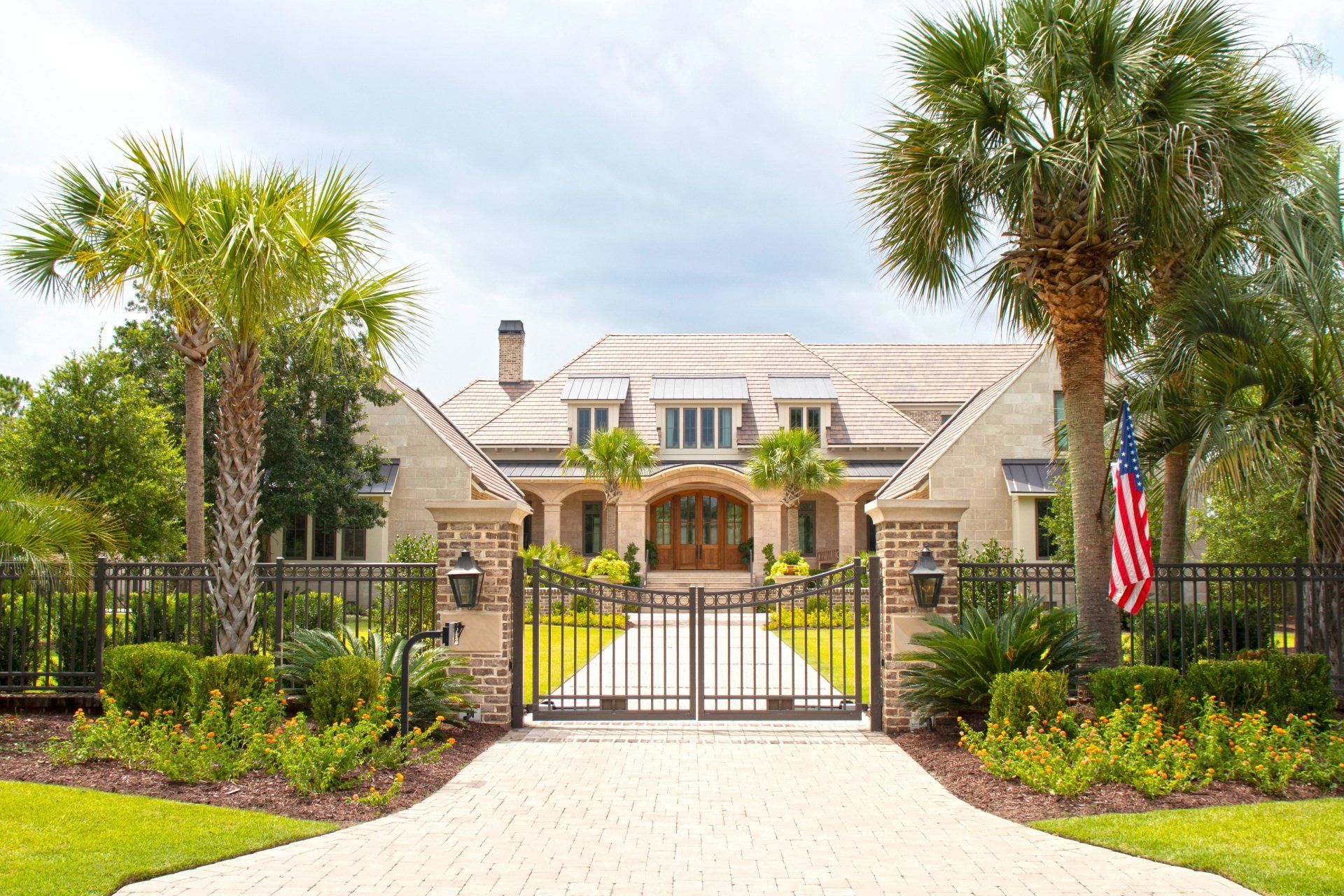 A large house with palm trees and an american flag in front of it.