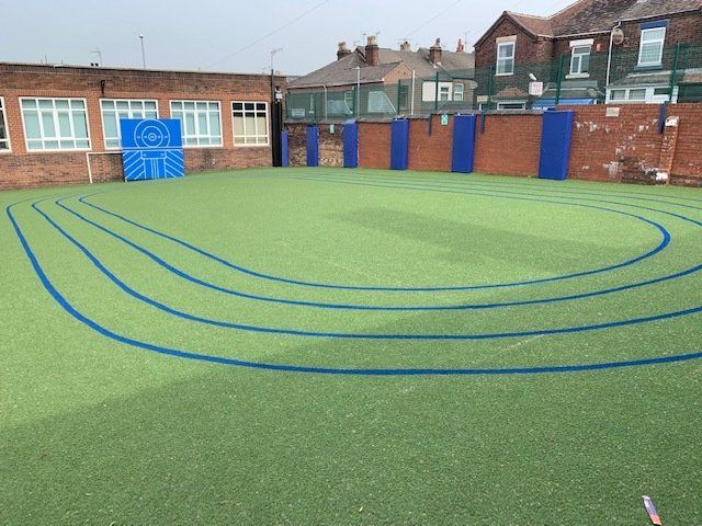 A green field with blue lines on it in front of a brick building