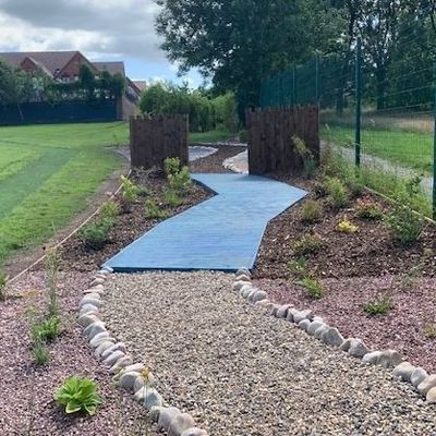 A blue walkway is surrounded by rocks and grass.
