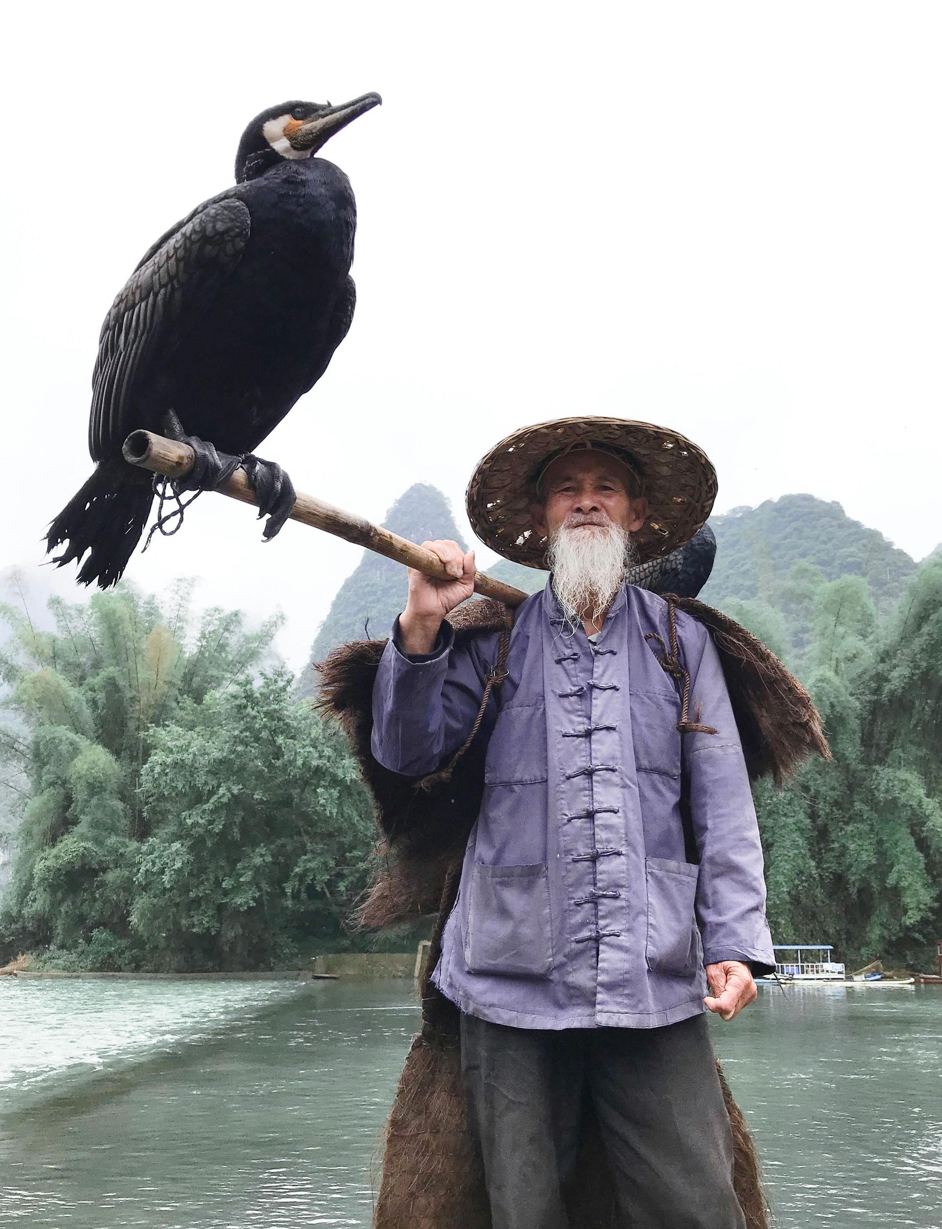 A man with a beard is holding a bird on his shoulder.