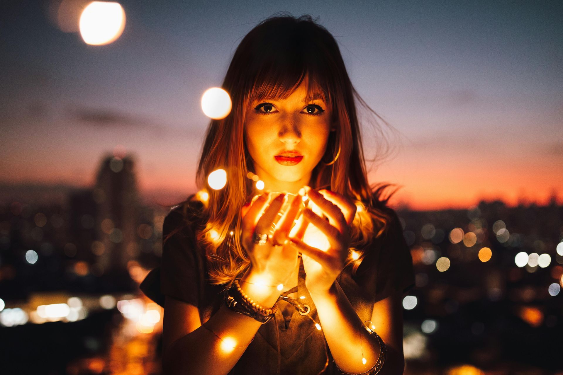 A woman is holding a string of lights in her hands.