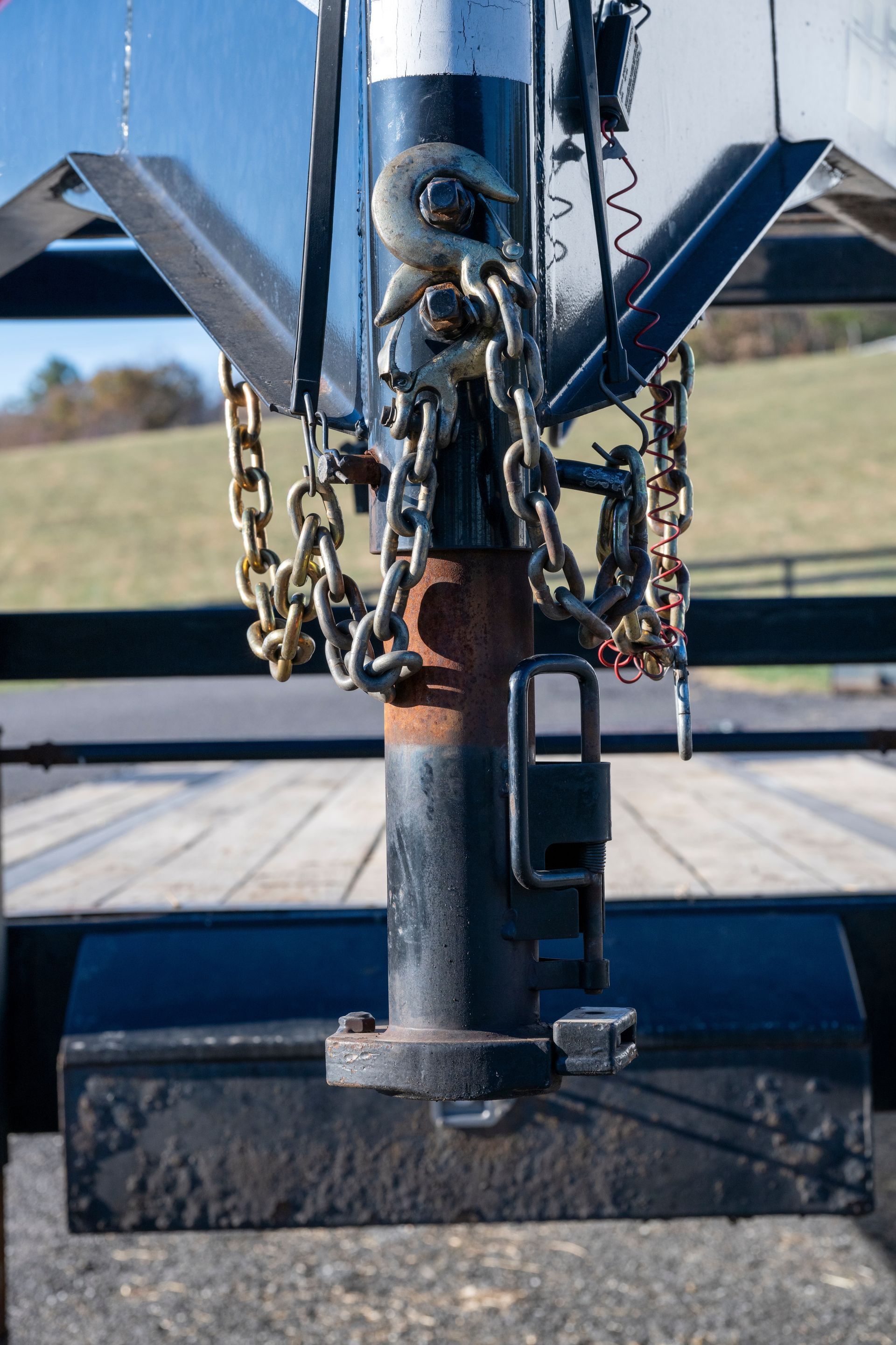 Metal hitch with chains and pins on a trailer tongue, outdoors in sunlight.