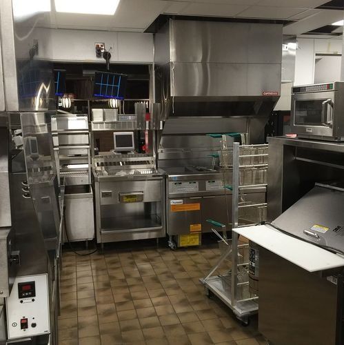 Commercial kitchen with stainless steel appliances, counters, and a tiled floor