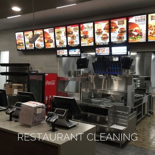 Empty fast-food restaurant counter with illuminated menu boards and cleaning supplies on the floor