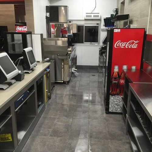 Empty restaurant kitchen aisle with stainless steel counters and red Coca-Cola refrigerators
