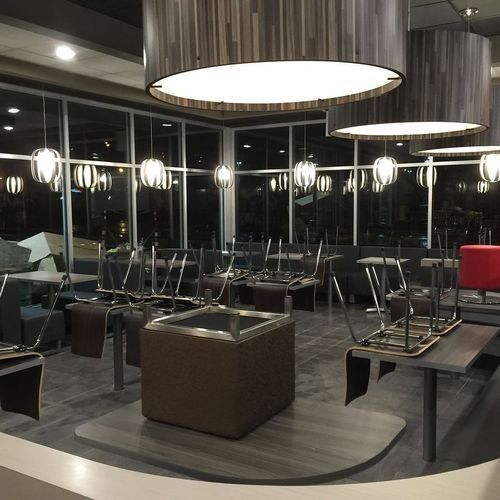 Empty modern lounge with suspended chairs, large hanging lights, and dark wood decor at night
