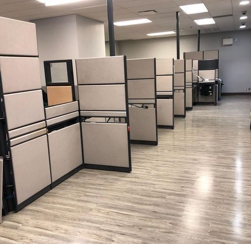 Office cubicles in an empty workspace with gray partitions and wood-look flooring