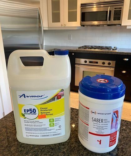 Two cleaning products on a kitchen counter, including a white jug and a white-blue bucket.