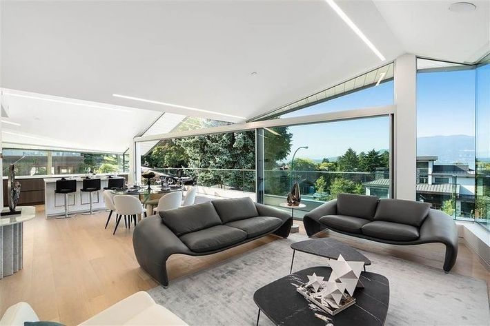 Modern living room with gray sofas, open-air design, and a view of trees and water