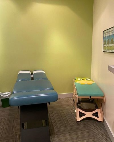 Medical exam room with two blue treatment tables against a green wall.