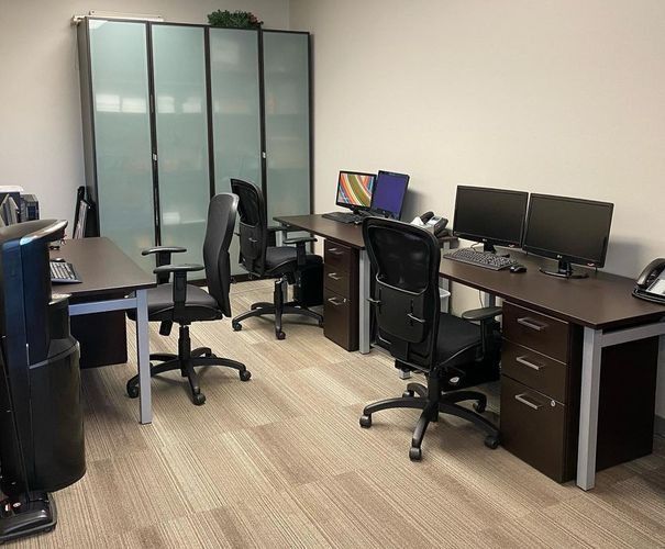 Modern office with desks, computer monitors, chairs, and frosted glass cabinets
