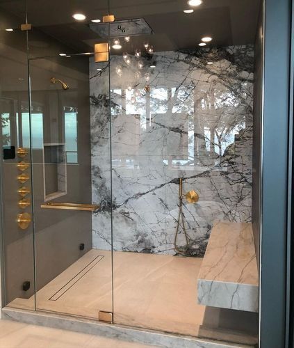 Modern glass shower with stone wall, bench, and large mirror in a sleek bathroom interior