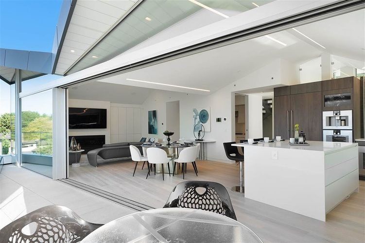 Modern open-plan living room and kitchen with large sliding glass doors and white minimalist decor
