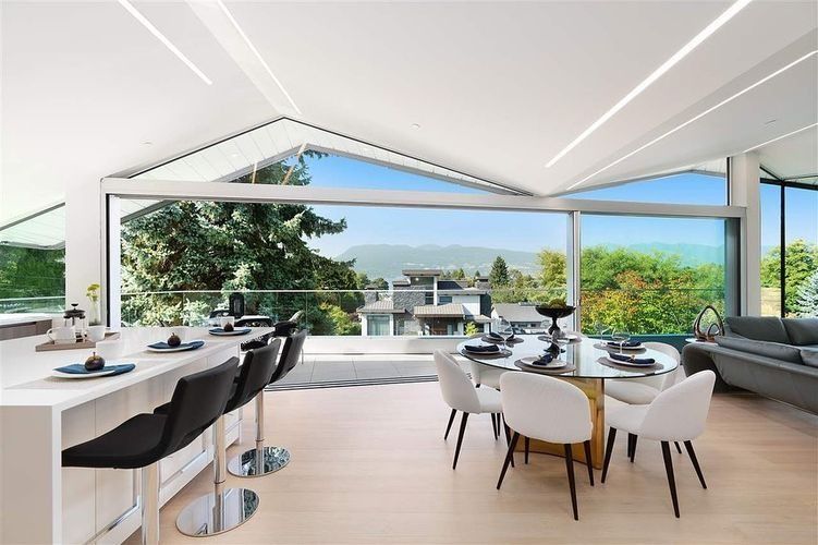 Modern open-plan dining room with white chairs, dark bar stools, and panoramic floor-to-ceiling windows