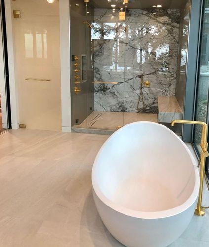 Modern lobby with light wood floor, marble wall, white egg-shaped chair, and brass handrail