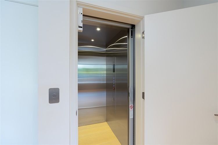 Open elevator with stainless steel doors in a white hallway