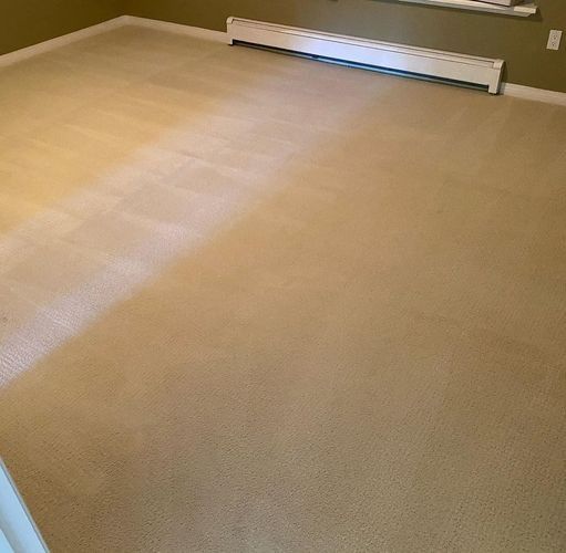 Empty beige carpeted room with a white baseboard heater along the far wall.
