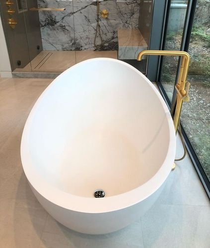 Modern white egg-shaped bathtub beside a floor-to-ceiling window in a spa-like bathroom