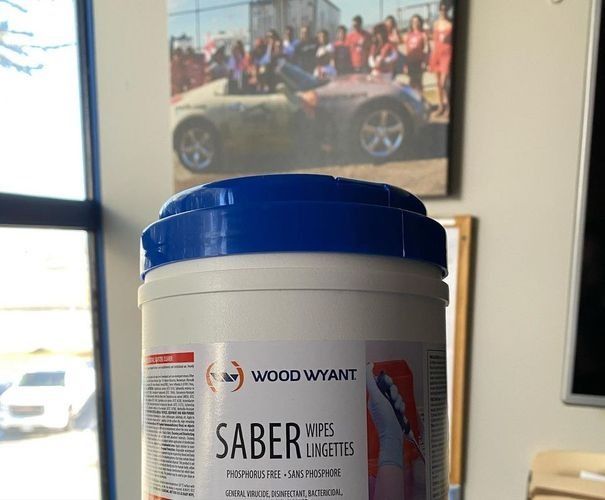 Blue-lidded supplement bottle labeled “Saber” on a table, with a framed car photo in the background