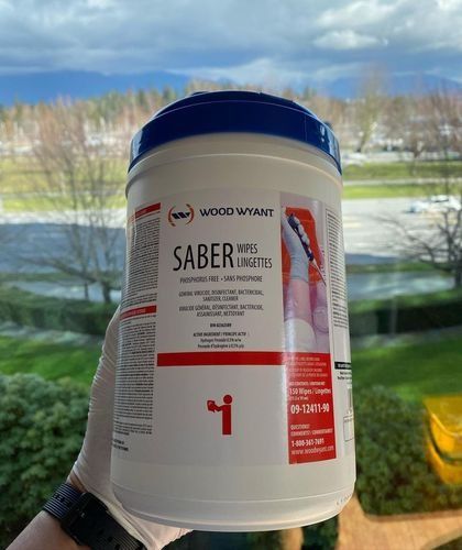 White SABER water bottle with blue cap held in front of a window and snowy landscape
