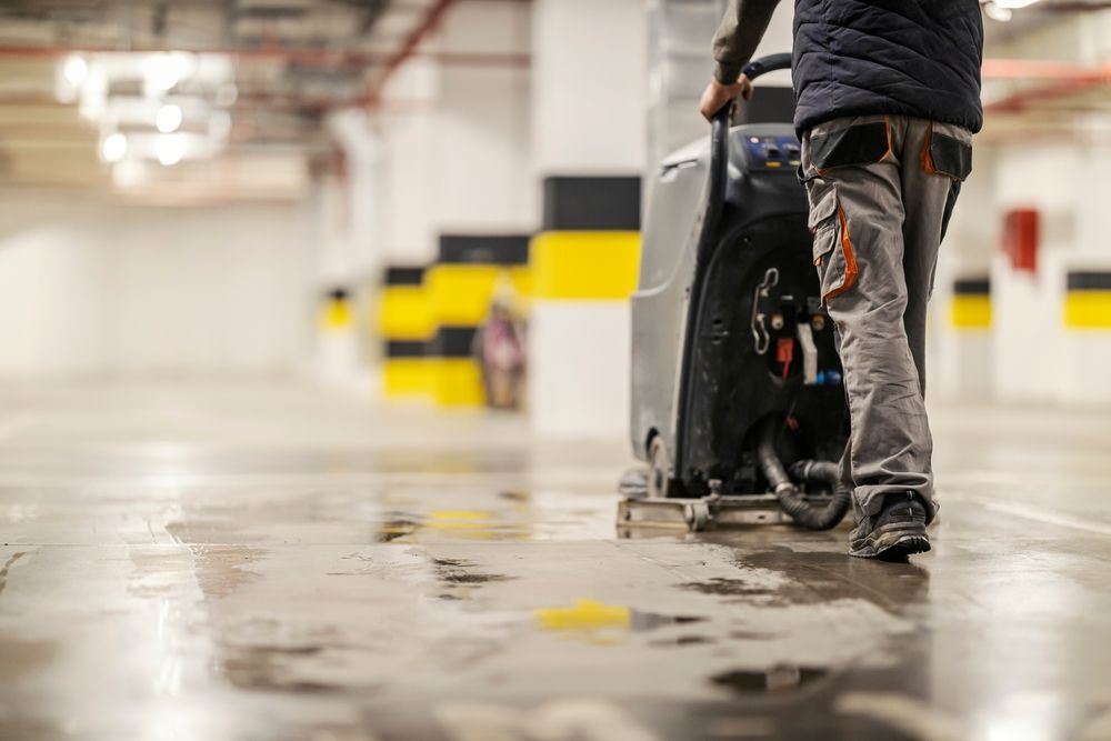 Person pushing a wheelchair in a wet parking garage with yellow-and-black striped columns