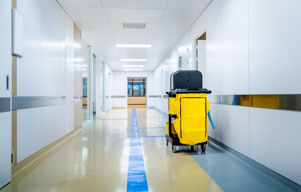 Clean hospital hallway with a yellow janitorial cart on the right and blue floor markings.
