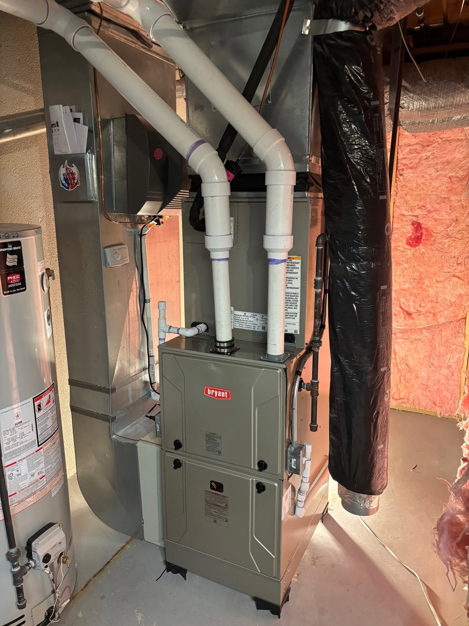 White HVAC/furnace unit with three silver ducts in a concrete basement