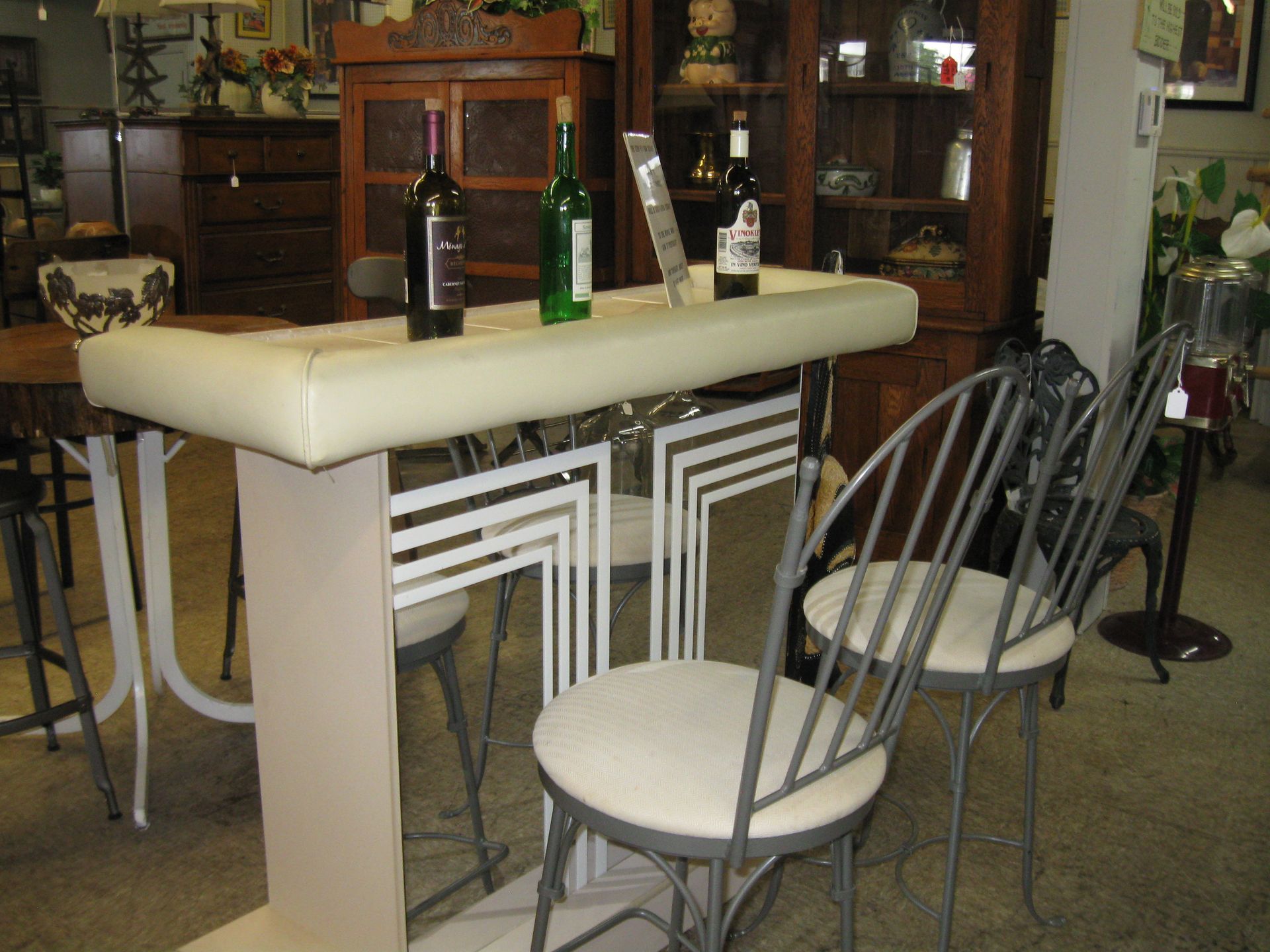 Modern bar table with bottles and metal chairs in a showroom setting