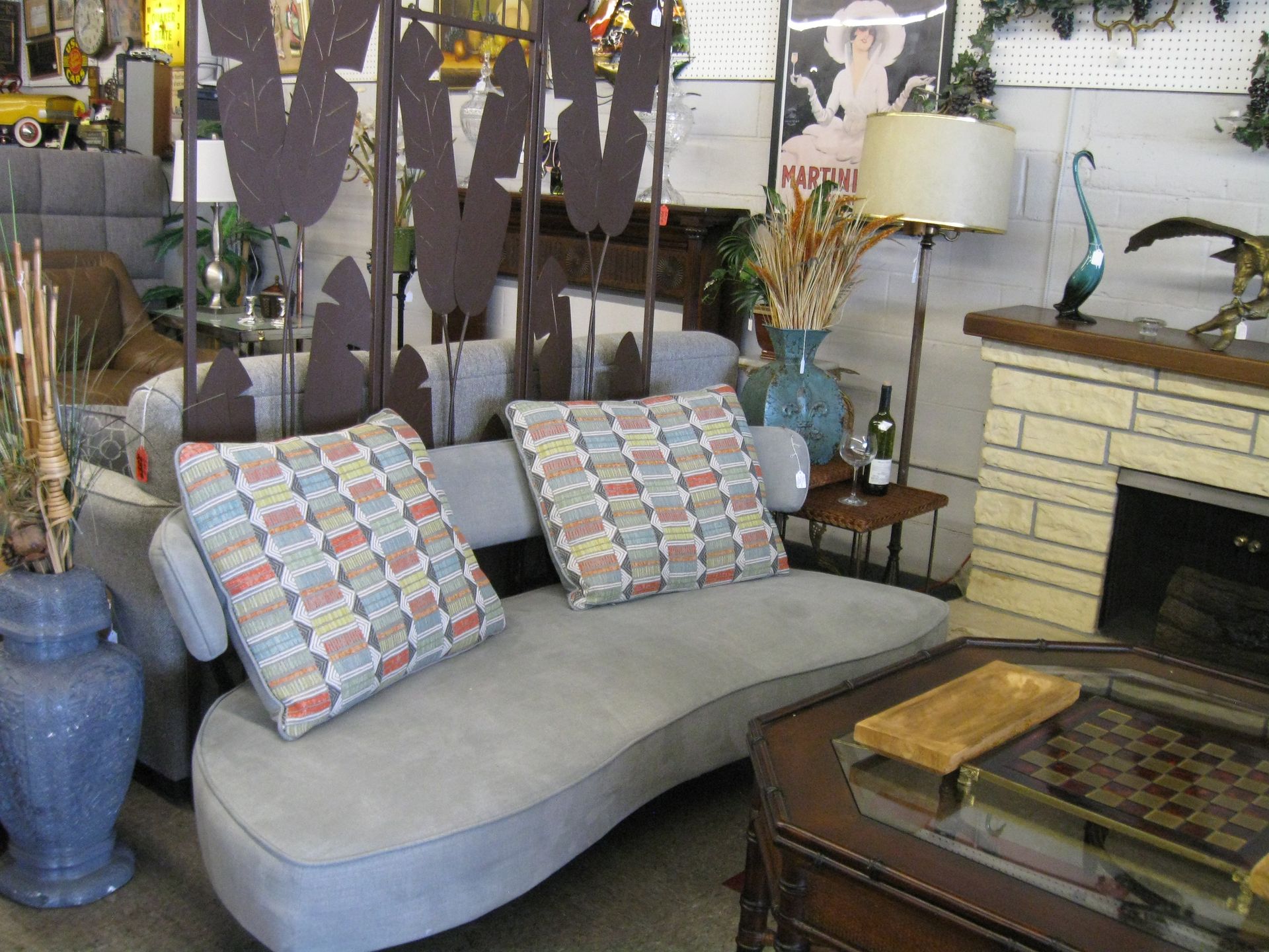 Curved gray sofa with patterned pillows in a cozy living room beside a fireplace and coffee table