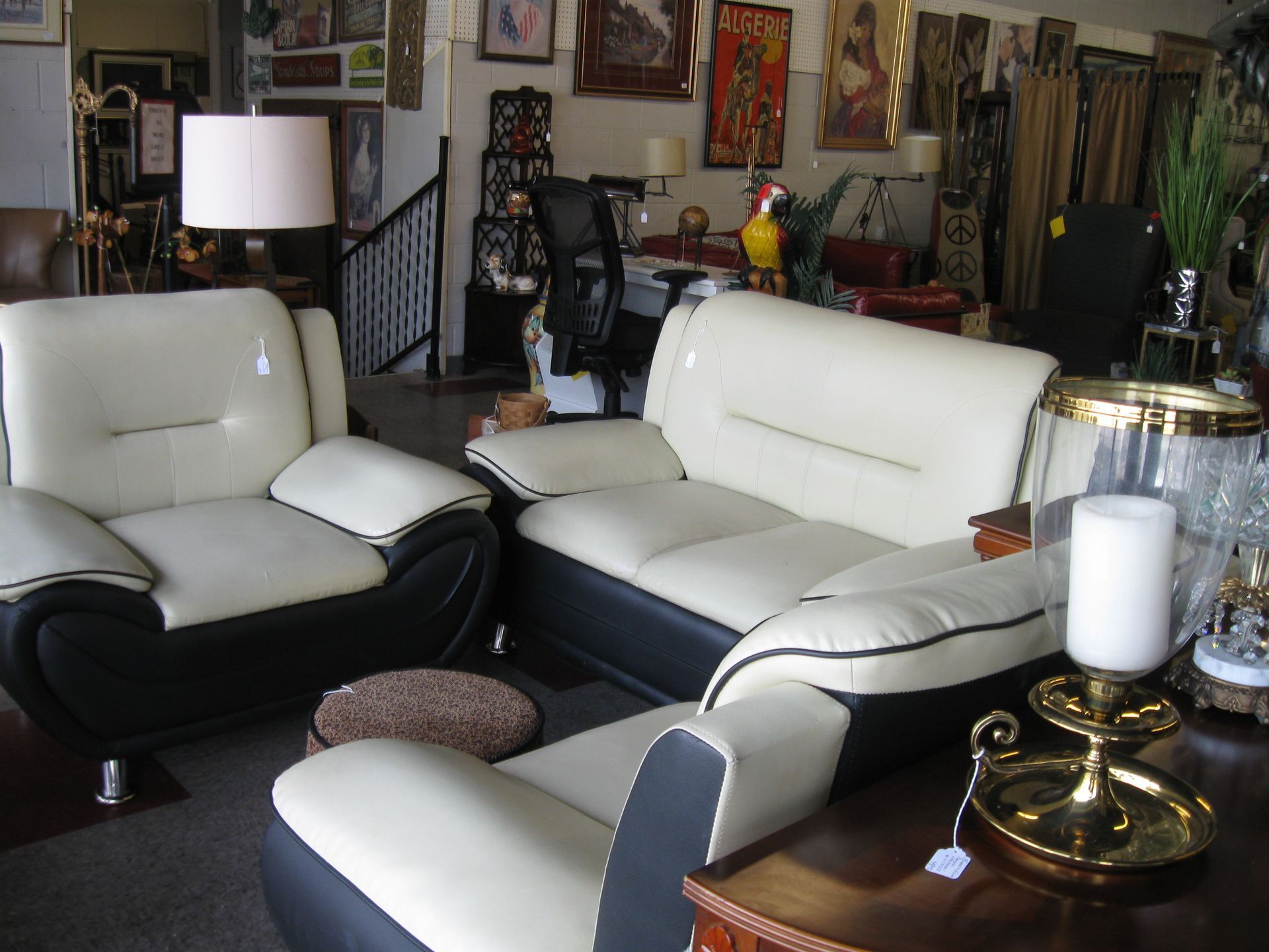 White leather living room chairs and sofa with black trim in a cluttered room