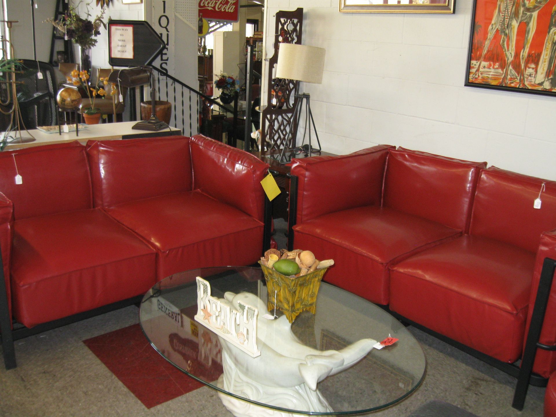 Red leather sofas around a glass coffee table in a cozy living room with lamps and wall art