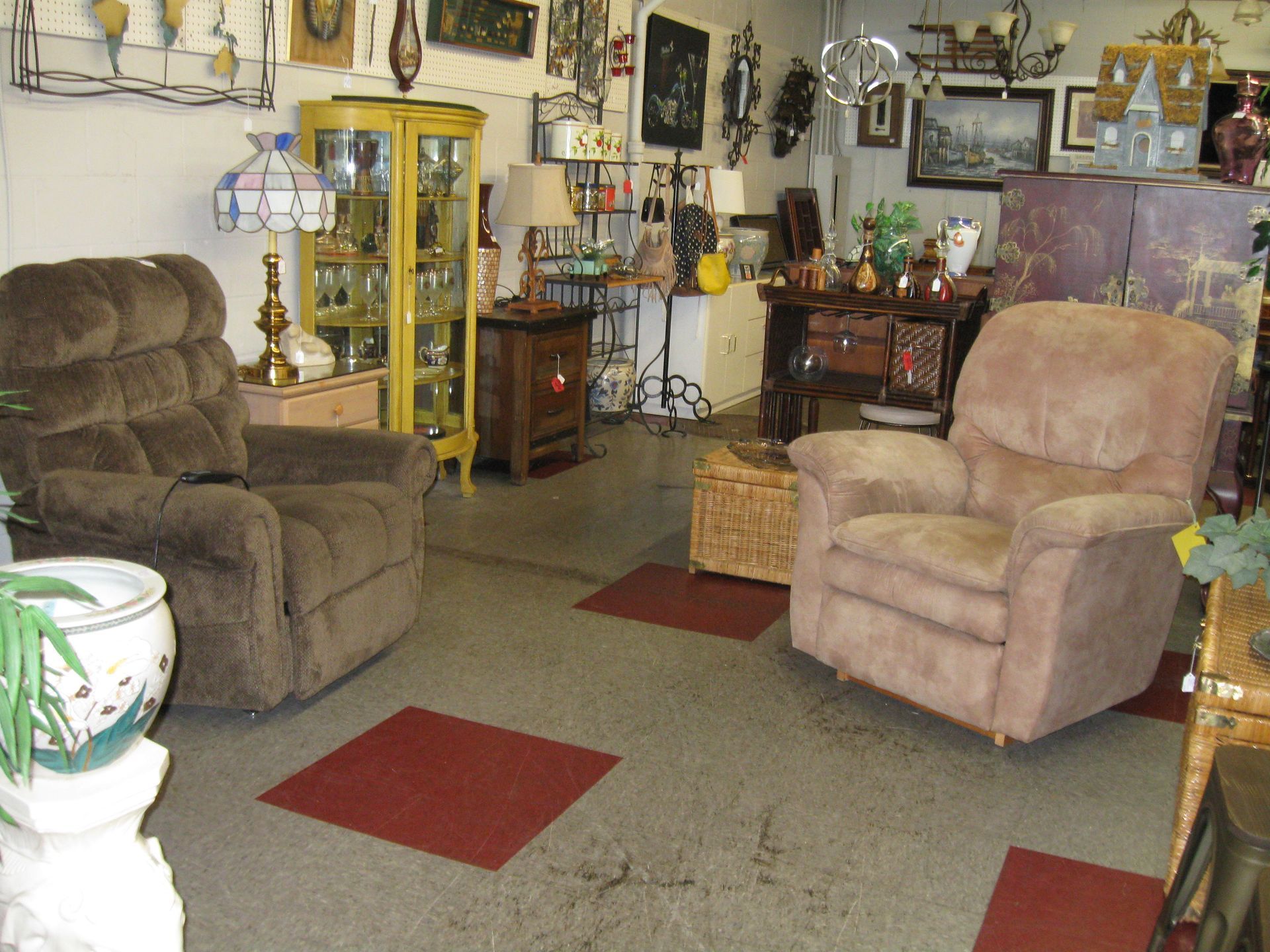 Cluttered living room with recliners, lamps, wall decor, and a patterned carpet