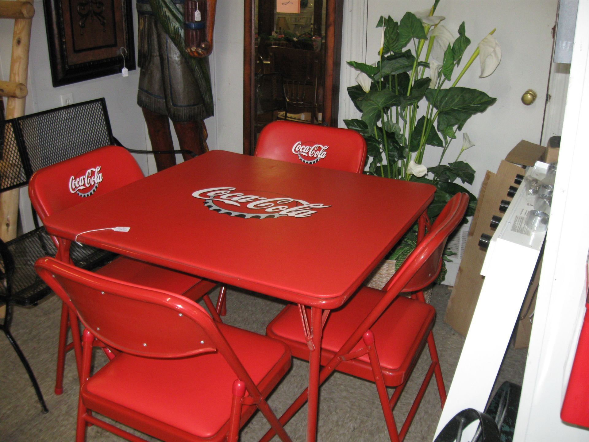 Red Coca-Cola patio table and chairs in a room with a large potted plant