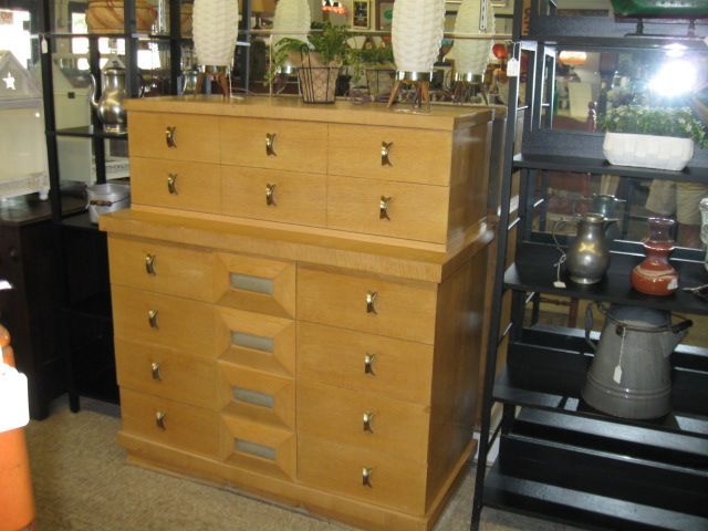 Wooden cabinet with drawers in a shop display, surrounded by glass and metal home decor items