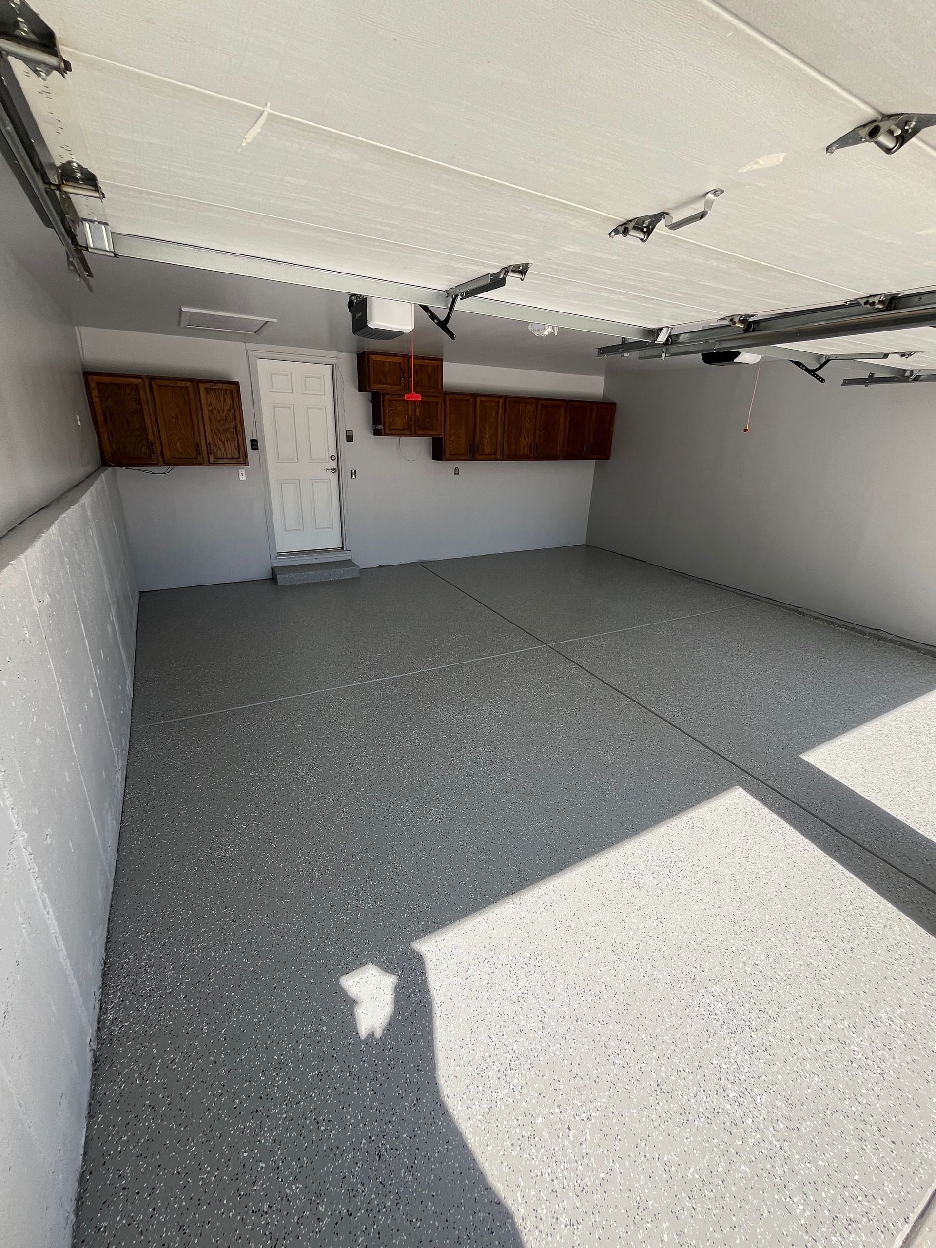An empty garage with a gray floor and a white door.