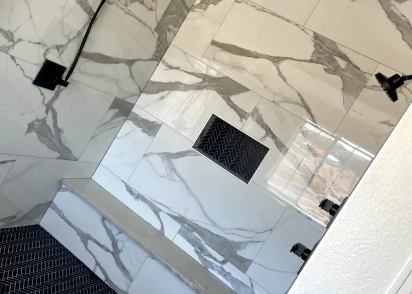 A bathroom with marble tiles and a shower head