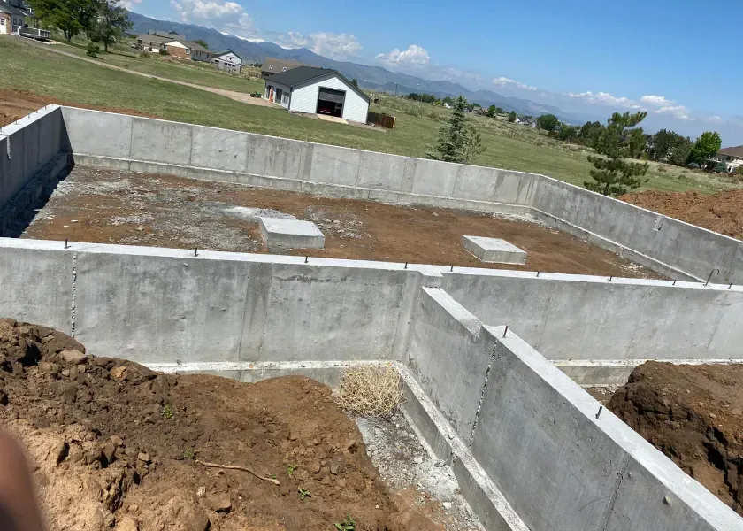 A concrete foundation is being built in a field with a barn in the background.