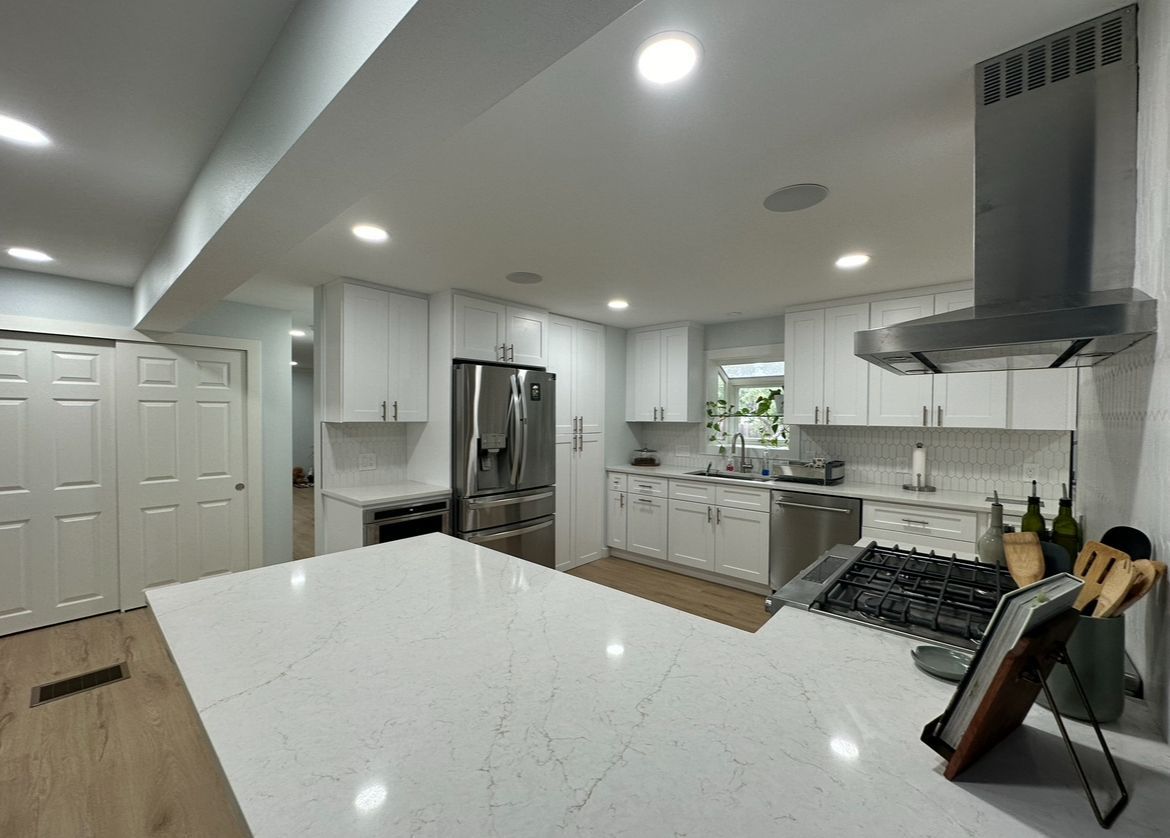 A kitchen with white cabinets , stainless steel appliances and a large island.
