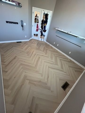 A room with a herringbone floor and a door.