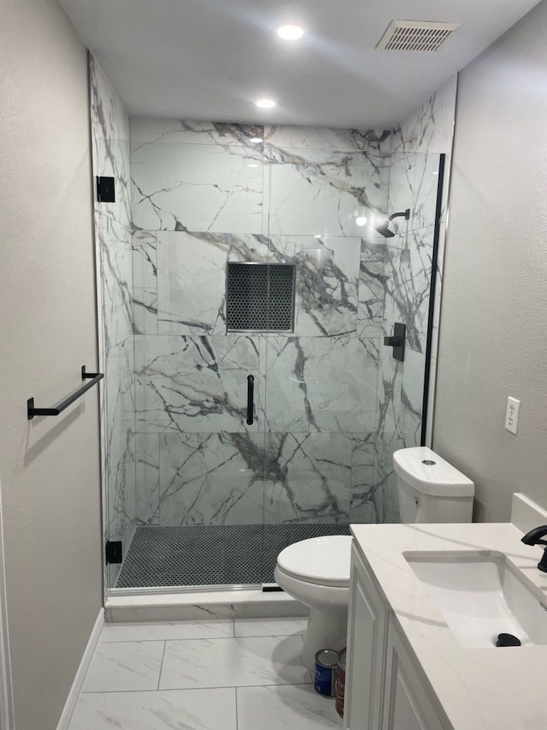 A bathroom with a toilet , sink and shower stall.