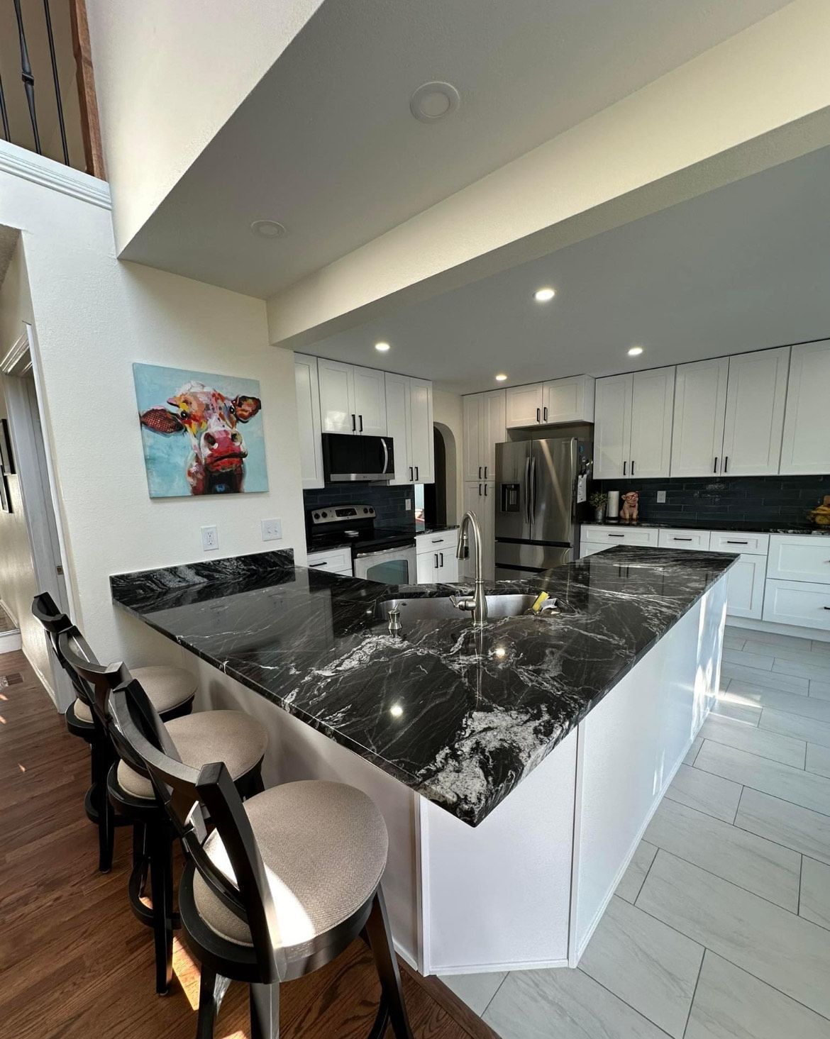 A kitchen with a large island and a cow painting on the wall.