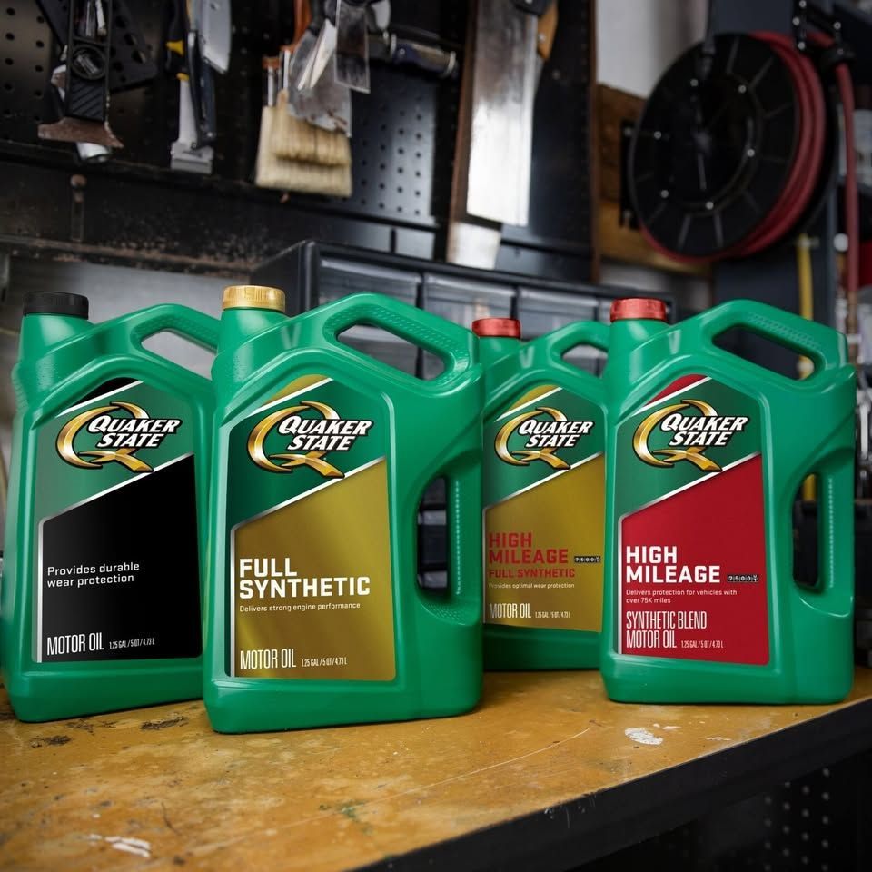 Four green Quaker State motor oil containers on a workbench; different formulas identified by colors.