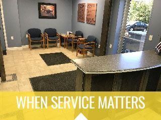 Small waiting room with blue chairs, a counter, and the text “WHEN SERVICE MATTERS” on a yellow banner.
