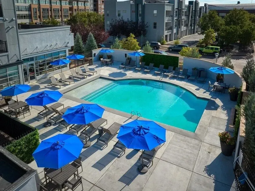 Outdoor swimming pool with blue umbrellas and lounge chairs.