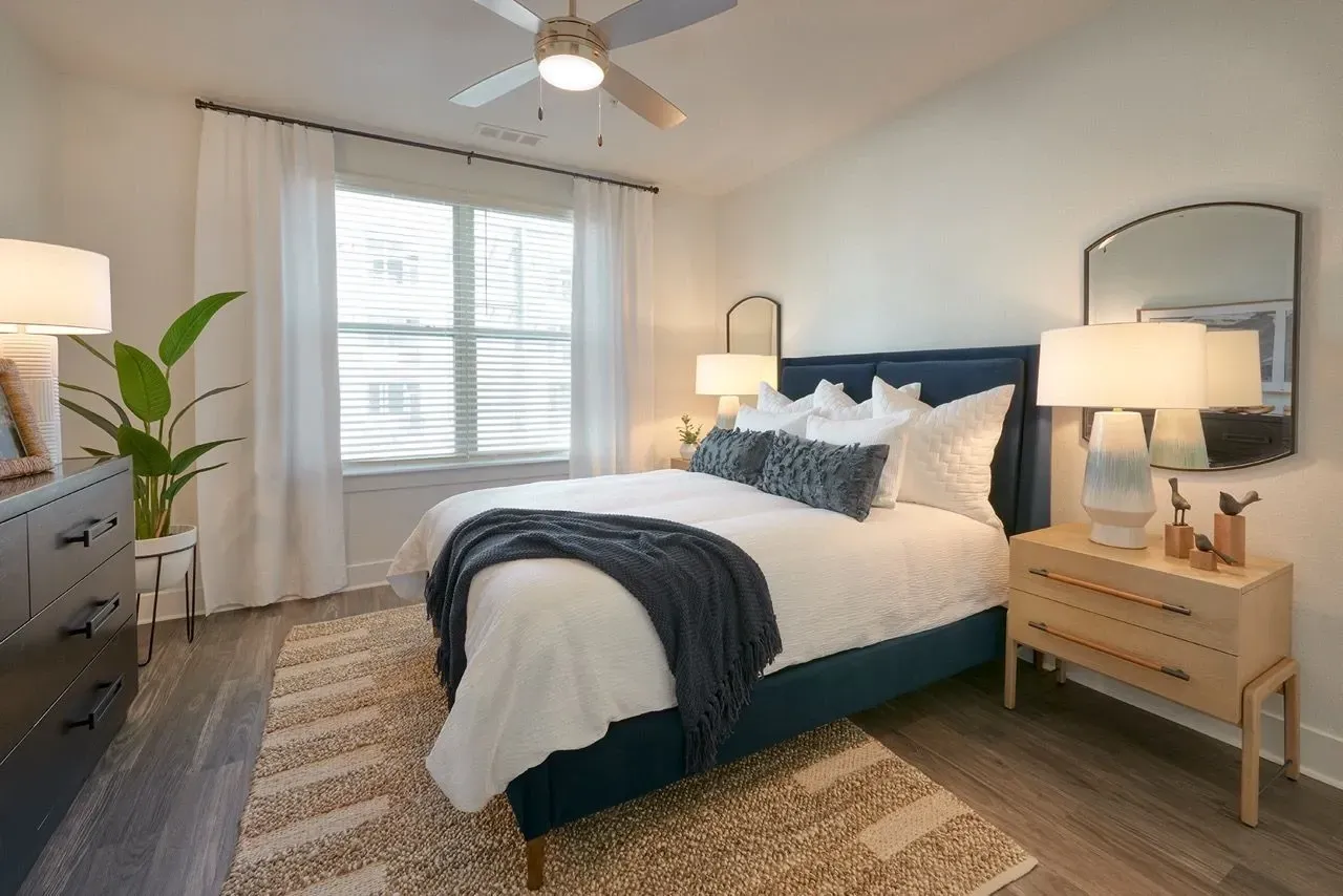 A beautifully staged bedroom with a queen-size bed, nightstand, dresser, and window.