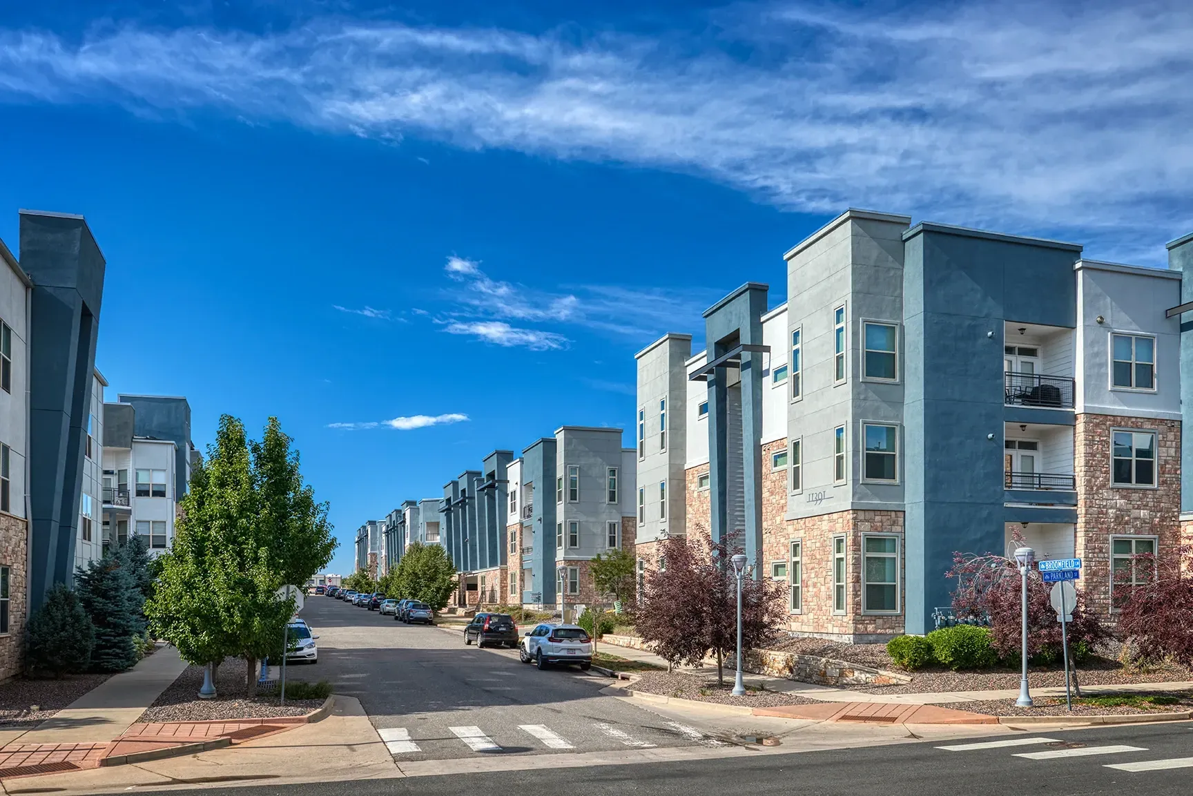 Exterior view of modern apartment buildings with blue and grey facades and stone accents.
