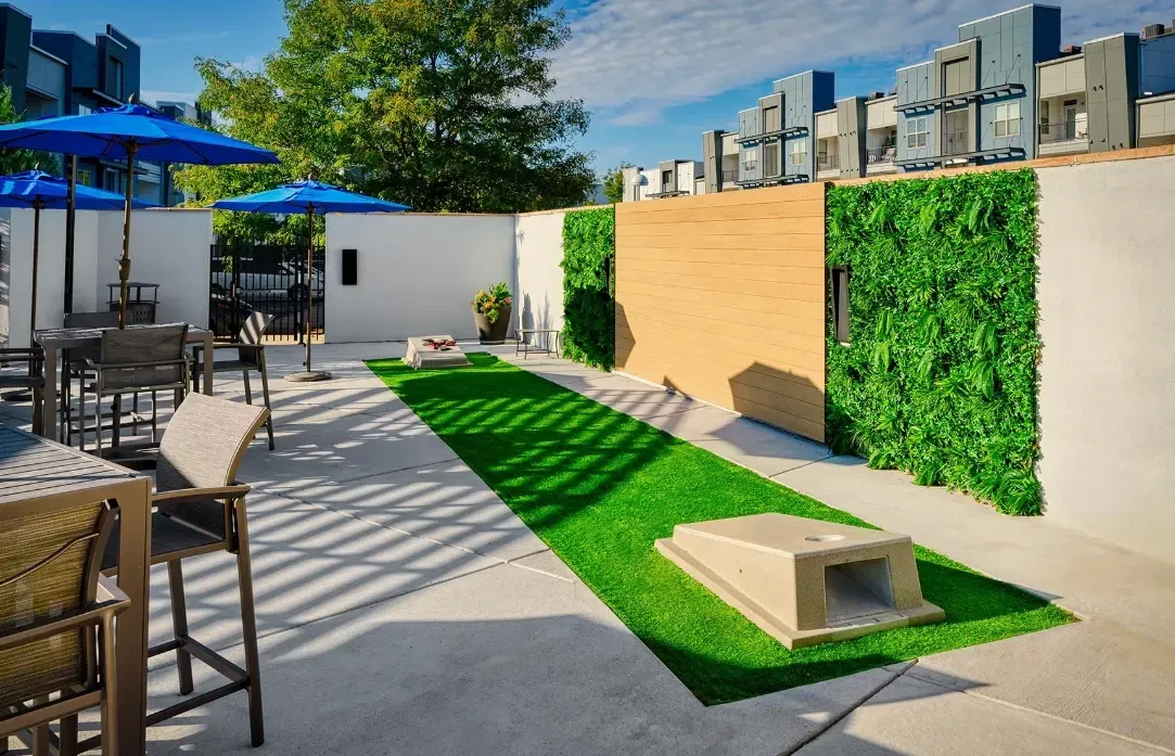 Outdoor lounge area with cornhole boards and seating under umbrellas.